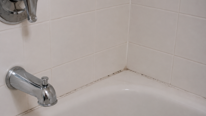 Tub corner showing early silicone discolouration along the joint where the tub meets the tile wall.